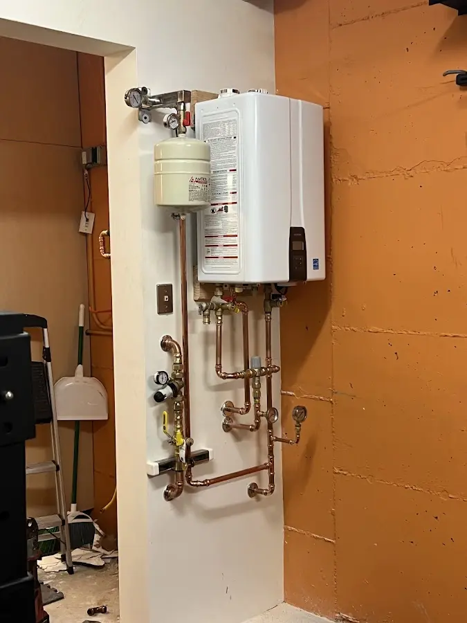 Plumbing technician inspecting water heater connections in Menallen